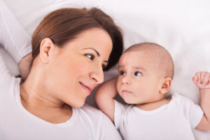 Young mother with her baby relaxing on bed